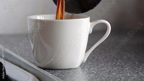 Male hand pouring coffee from a turk into a white cup, close-up
