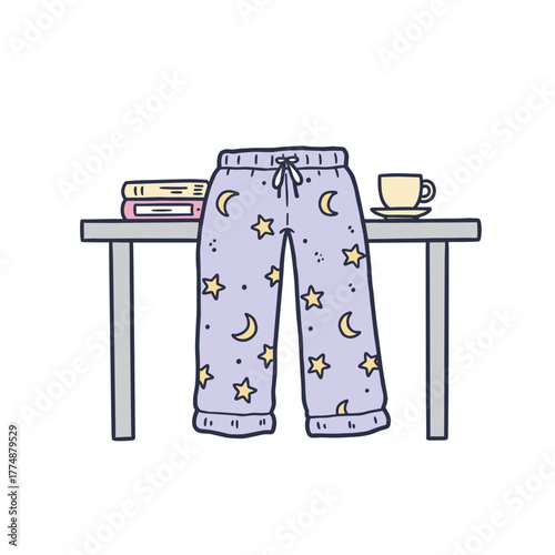 Casual pajama pants with stars hanging on table beside books and cup  