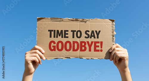 Person holding cardboard sign time to say goodbye against sky