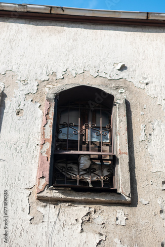 Close-up of a historic building window protected by iron bars. Weathered architectural details showcase age, heritage, security features, and traditional construction craftsmanship.