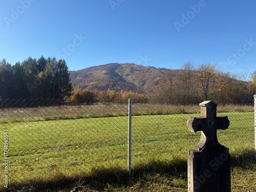 Old rural cemetery in autumn with gravestones and a field under a clear blue sky