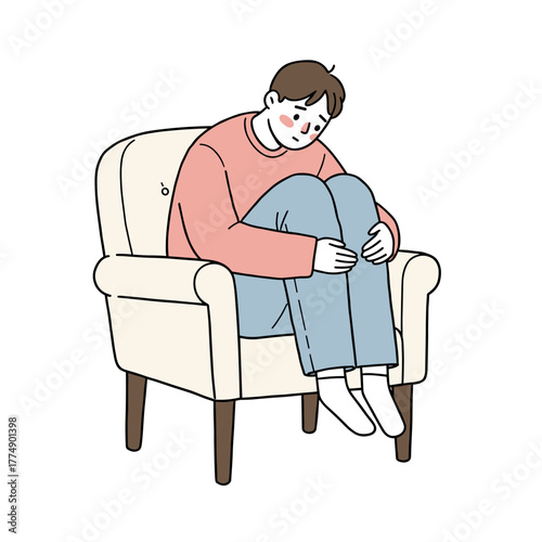 Young man sitting in armchair, hugging knees and looking down  