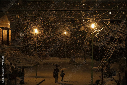 Daily Life in Japan 
Mother and young child walking through a small city park on a snowy evening