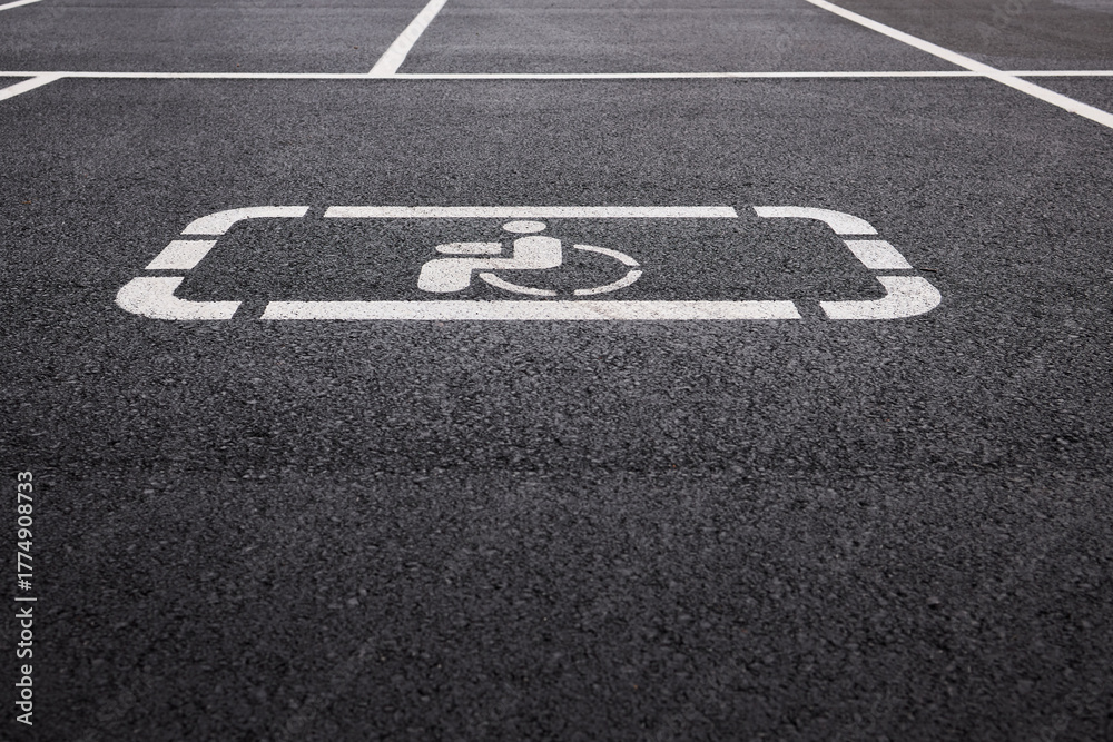 Fototapeta premium car parking space on asphalt, white worn markings, textured pavement, Handicap sign represents accessibility, inclusivity, equal rights, and consideration for individuals with disabilities