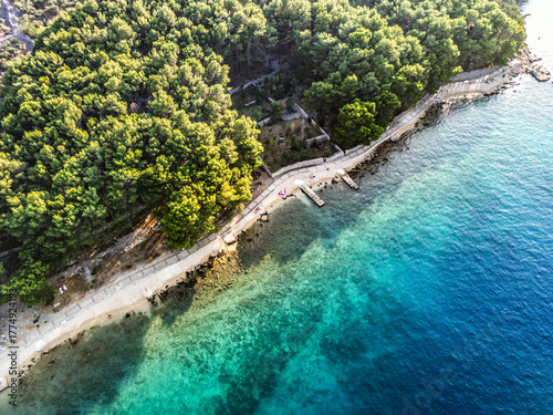 Top down aerial view of beautiful Cres island with olive plantations divided by the old drywalls and beautiful, turquoise sea splashing the shore