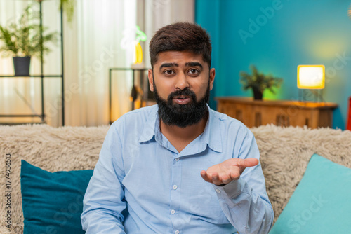Fotografia Indian man at home rolls eyes showing ironic reaction during smartphone chat dismissing odd comment
