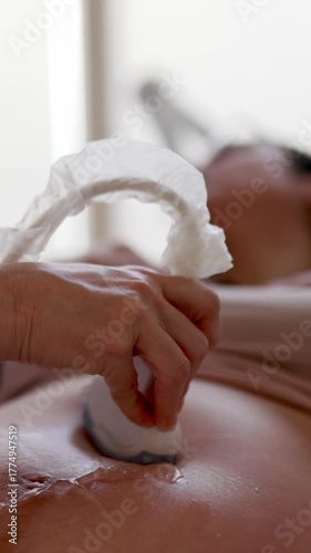 Professional gynecologist performing prenatal ultrasound examination, scanning pregnant woman's belly to monitor fetal development and maternal health