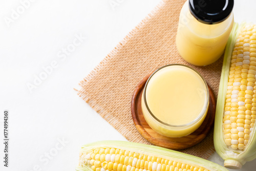 Sweetcorn milk in glass and bottle with fresh sweetcorn on white background, Alternative milk from plant, dairy free