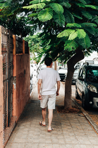 A guy walks along a path with tropical trees on an island.