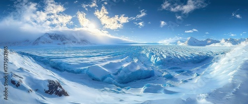 Vast icy glacier surrounded by snow-covered mountains under a bright blue sky with scattered clouds, evoking a sense of cold and tranquility