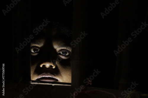 Artistic woman’s face lit in darkness, expressing resilience, life, and emotion through shadow and subtle human expression.