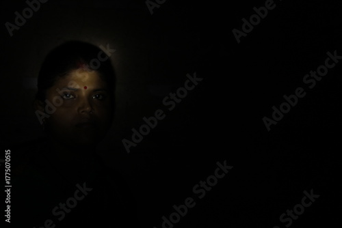Dramatic low-light photograph of an Indian woman wearing a traditional saree, reflecting dignity, calmness, and emotional depth through expressive lighting.
