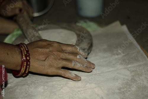 Close-up of an Indian woman’s hands rolling dough on a wooden board to make chapatis, symbolizing tradition, love, and the essence of home-cooked food in Indian households.
