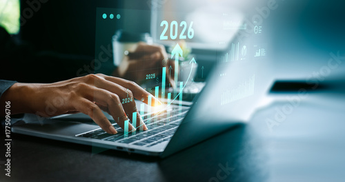 Businessman analyzing digital financial growth charts with upward trends and 2026 target, using laptop and stylus for strategic planning, investment forecasting, future business performance analysis