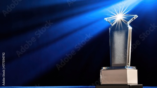 Shiny acrylic award trophy illuminated on a dark blue stage