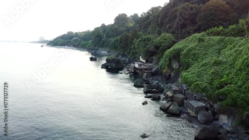 Morning scene of rugged shoreline, Serene oceanfront with rocky cliffs illuminated, Vast scenic seaboard displaying peaceful waves and rugged stones in gentle morning