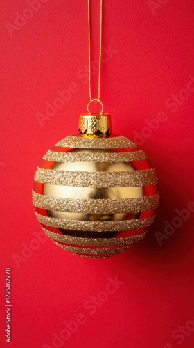 Gold striped christmas ornament hanging on red background festive decoration for joyful holiday celebration and winter season
