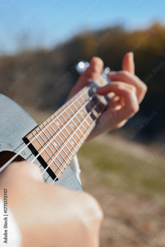 Φωτογραφία Close up of female hands play ukulele in autumnal park