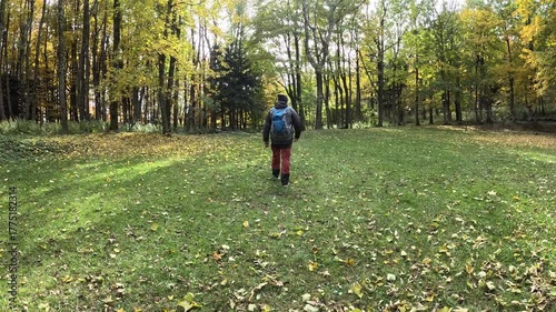 Rear view of senior man hiking through the autumn forest