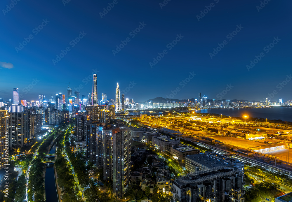 Obraz premium Shenzhen city skyline and waterfront reflecting the vibrant lights during the blue hour after sunset.