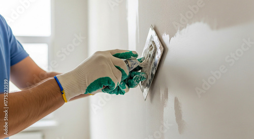 Skilled handyman smoothing plaster on interior wall with trowel tool