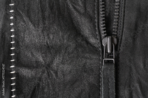 Zip with a tab on a black suede jacket with white contrasting seams