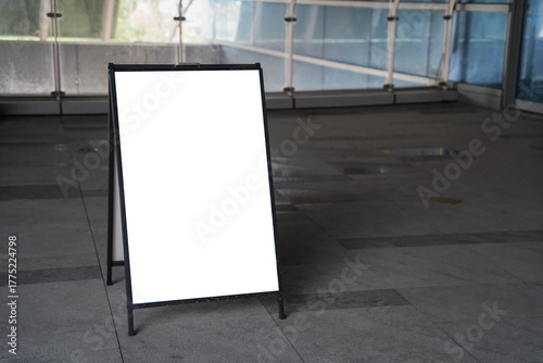Blank white outdoor advertising stand sandwich board mock up template. Clear street signage board placed by an outdoor dinning area of a restaurant.