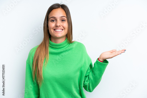 Young caucasian woman isolated on white background holding copyspace imaginary on the palm to insert an ad