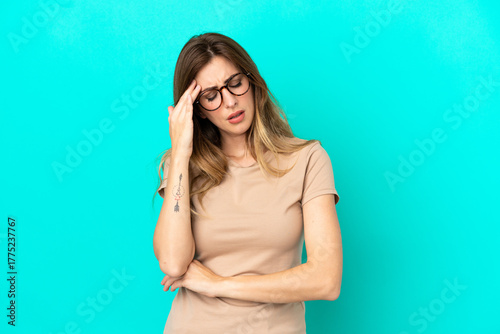 Fotografie Young caucasian woman isolated on blue background with headache