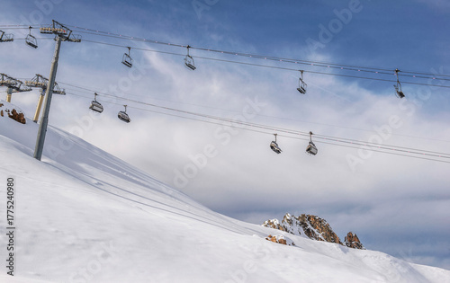 view on freshly snow-covered ski slope with the ski lifts under white cloud i...