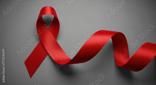 A long, flowing red awareness ribbon for HIV/AIDS or heart disease, waving on a simple grey background.