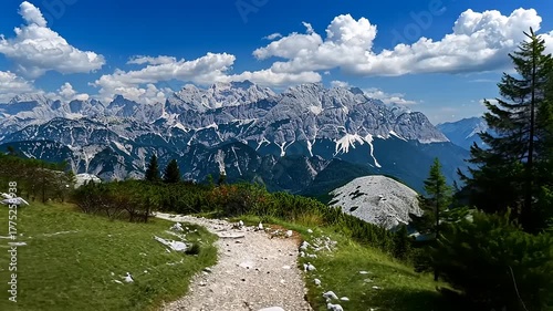 Scenic mountain trail leading to majestic peaks under a blue sky with fluffy clouds, perfect for