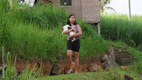 A young woman walking while carrying a cat.