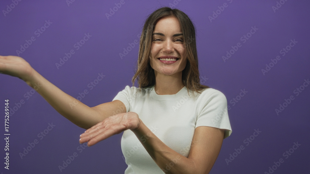 Obraz premium Young hispanic woman presenting open hands with smiling expression in studio against bright purple backdrop; welcome happiness.