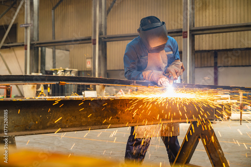 Welder use carbon air arc gouging for hot work cutting or gouging heavy metal steel structure in the fabrication factory.