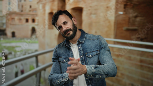 Canvas Print Hispanic man with beard gesturing in old town rome wearing denim jacket against