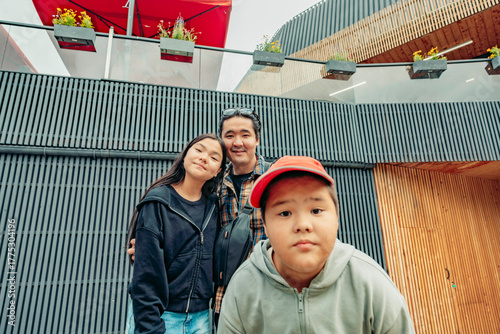 Fotografija A young Asian girl and a middle-aged Asian man smile together, while a young Asian boy poses in front