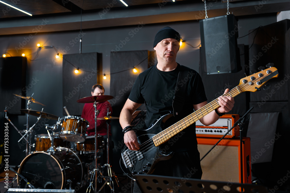 Fototapeta premium Musicians in a Studio Practicing With Bass Guitar and Drum Set