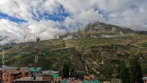 A colorful rainbow appears over a flowing stream and arid desert landscape in darcha, north of India, capturing the striking beauty of this unique region.