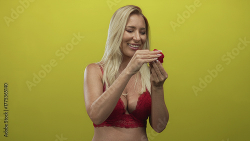 Fotografija Caucasian blonde woman with exposed cleavage smiling while opening a red jewelry box in studio; romantic surprise