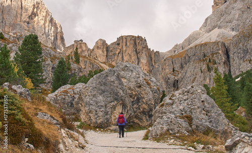 A female hiker in a trail towards the Vajolet Towers surrounded by mountains of Catinaccio group. Paul Preuss Refuge in a cliff with panoramic position on a rocky spur overlooking the Vajolet Valley.