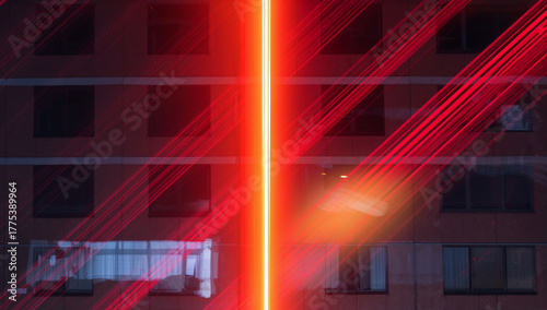 Abstract building facade with vibrant red light streaks and a bright vertical beam