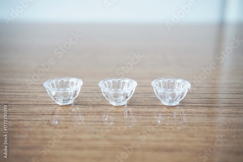 Three Miniature Clear Bowl on a Wooden Surface Three Small Clear Shot Glasses on a Wooden Table