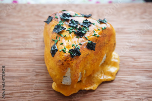 1 on 1 replica of japanese onigiri topped with mentai sauce and seaweed on wooden background