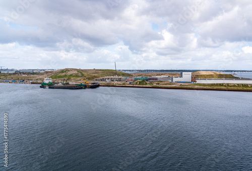 A cargo ship is docked near the construction site in Nordhavn, Copenhagen Denmark, showcasing ongoing harbor development and building expansion near the water.

