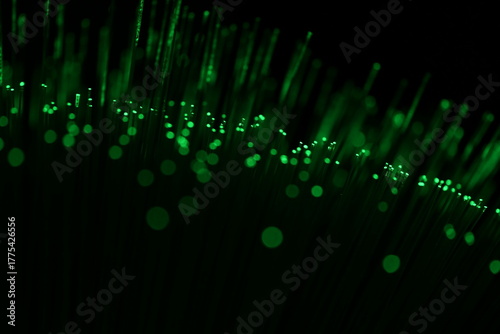 An abstract close-up of luminous green fiber optic strands and bokeh, suggesting eco-friendly data and sustainable technology on a dark background.