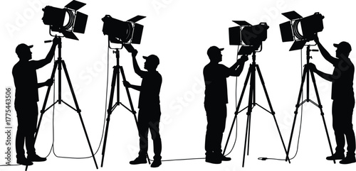 Silhouette of film crew technicians adjusting studio lighting equipment on tripods, professional photographers setting up lights for movie and video production scene