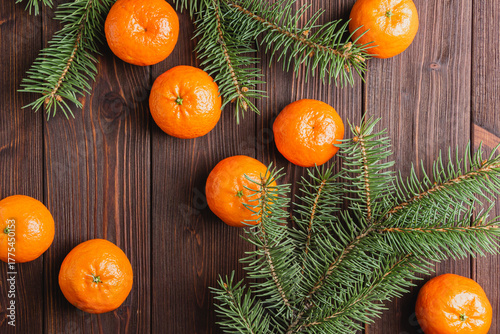 Tangerines with fir branches on a brown wooden table.