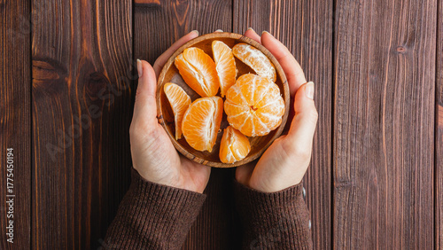 Tangerines on a plate on a brown wooden table.