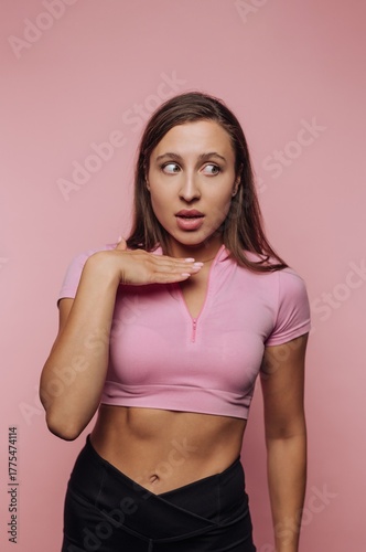 Woman in pink top looking surprised against pink background